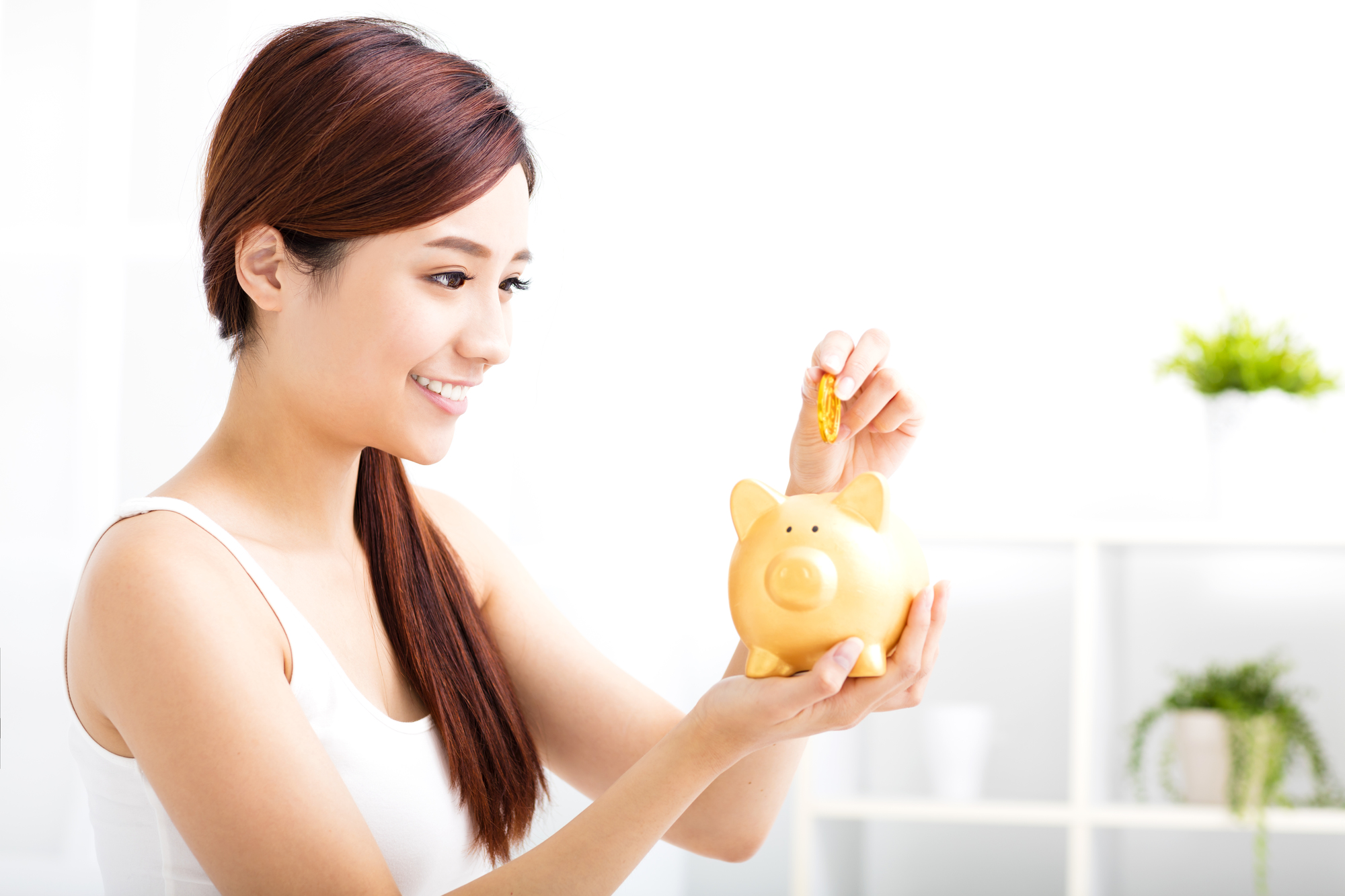 Happy young woman saving money in the piggy bank